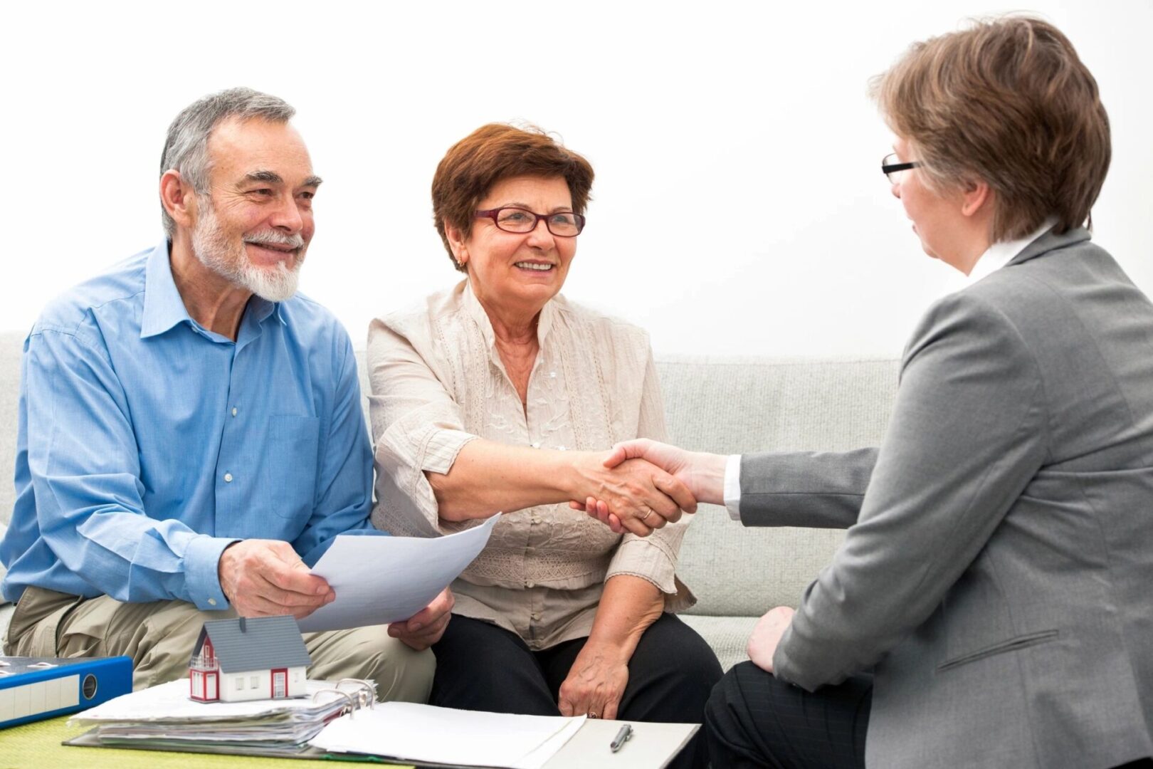 A couple of people shaking hands over paperwork.